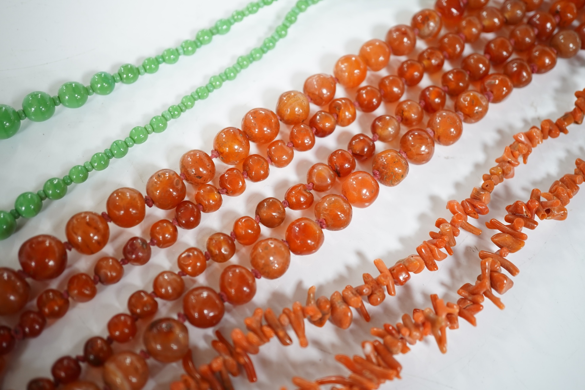 A micromosaic brooch and a group of bead necklaces, comprising: a micromosaic brooch depicting the Forum, length 4.6cm; together with a carnelian bead necklace; a coral branch necklace; and a green glass bead necklace